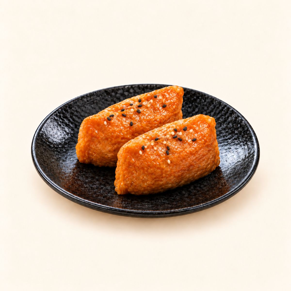 Inari sushi with sesame seeds on top, in a black dish